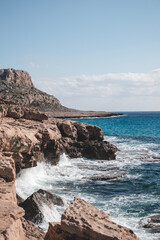 Fototapeta na wymiar Beautiful seashore with lagoon sea and waves in front of the Cape Greco mountain