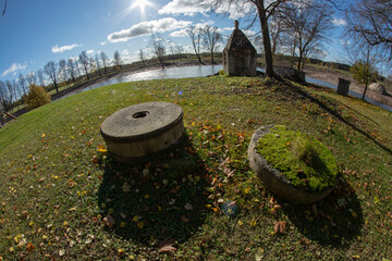 Pair of Old Millstones Covered in Moss and historical smokehouse - 532876022