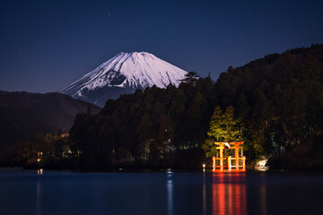Snow capped Mount Fuji at night with torii gate from Lake Ashi Hakone Japan
