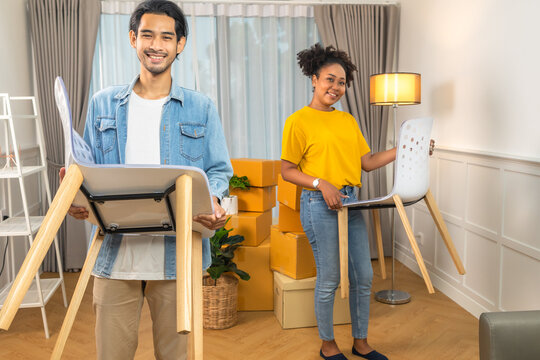 Happy African American young family bought new house. Mom, Dad, and child smiling happy hold cardboard boxes for move object walking into big modern home.
