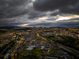 Aerial view of dramatic storm clouds over sprawling town lights at dawn