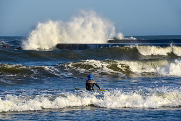 Naklejka premium Female surfer looking at dangerous waves by pier