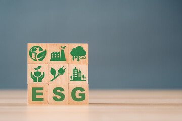 Wooden cubes with abbreviation ESG standing with other ESG icons on white background. Copy space. ESG concept of environmental, social and governance. Sustainable corporation development.