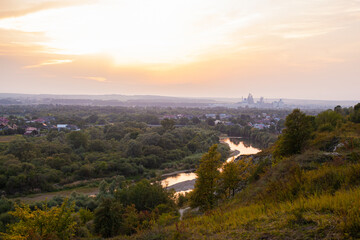 Fototapeta premium Panoramic view of the city of Ivano-Frankivsk. View of mountain hill and industrial power station oland behind at evening. Sunset over Ivano Frankivsk city in Ukraine. Landscape with hills and river.