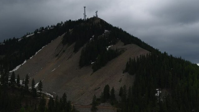 High aerial of northern idaho ski resort and mountain summit covered in talus rocks with stormy dramatic skies in background