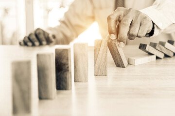Close-up hand prevent wooden block not falling domino concepts of financial risk management and...