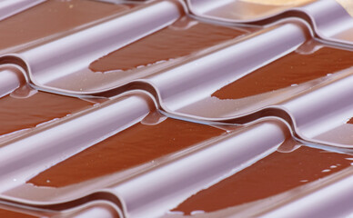 Water on the brown metal roof of the roof of the house.