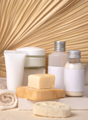 Cosmetic bottles and soap bars on stone against dry beige palm leaf close up, label mockup