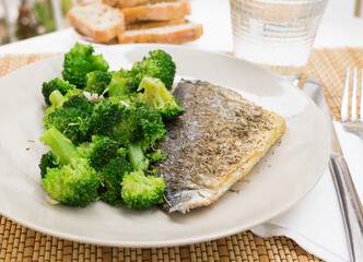 dish of fried dorado fish fillet with boiled broccoli