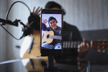 Asian influencer playing guitar during podcast or live video broadcast for the audience from the...