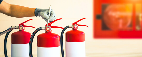 Close up fire extinguisher and firefighter checking pressure gauge level for protection and prevent...