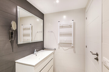 Modern bathroom with gray tiles, electronic heater and rectangular large mirror with lighting