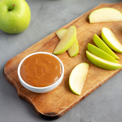 Homemade Caramel Apple Dip on a rustic wooden board, side view. Close-up.