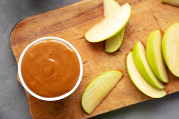 Homemade Caramel Apple Dip on a rustic wooden board, top view. Flat lay, overhead, from above. Close-up.