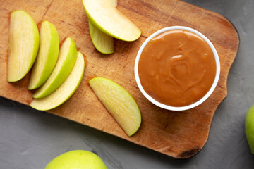 Homemade Caramel Apple Dip on a rustic wooden board, top view. Flat lay, overhead, from above. Close-up.