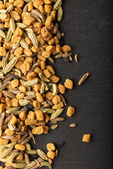 Panch phoron  or panchpuran  tradicional Indian five spice seeds blend for cooking consisting of fenugreek, fennel, cumin, zira on black stone.