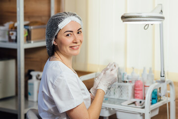 Beautiful woman doctor in mask on face, smiling and putting on medical gloves