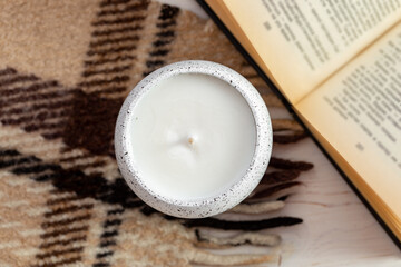 Beautiful composition with a book candle and a plaid on a wooden table. Zen and relaxation concept.