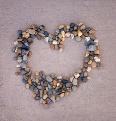 Fototapeta na wymiar A heart shape made with small pebbles on top of a cement surface.