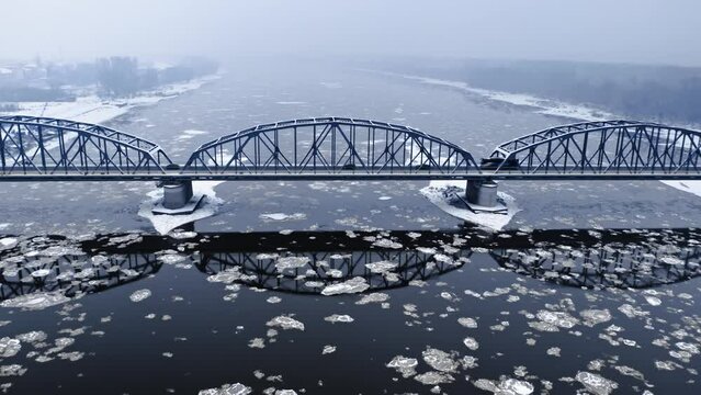 Snowy bridge and floes on river in winter.