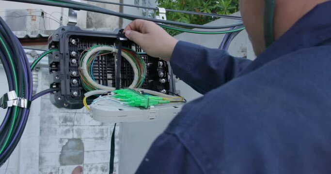 An internet technician is repairing or maintaining a fiber optic connection by opening a fiber optic connector.