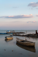 Boats on water, colorful sky and clouds with reflection on water and fishing boats on the sea