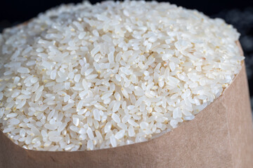 a pile of white rice in a paper bag and on the table