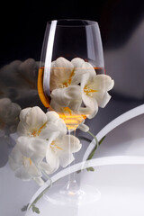 Double exposure of glass of wine over white freesia, vertical picture