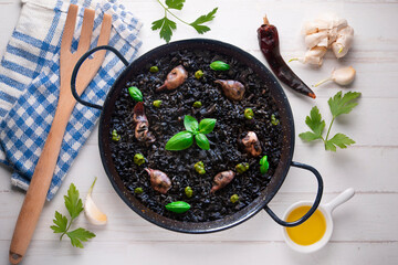 Black paella with squid and pistachio pesto. Tapa paella typical recipe from the Spanish Mediterranean coast.