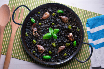 Black paella with squid and pistachio pesto. Tapa paella typical recipe from the Spanish Mediterranean coast.