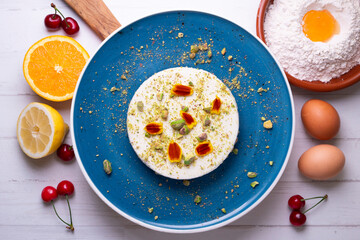 Yogurt and pistachio mousse decorated with red flowers on a blue ceramic plate. Traditional French recipe.