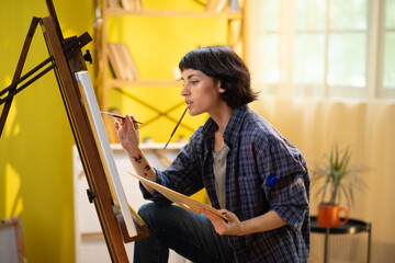 A close up shot of a the back on an artistic woman painting a beautiful piece of art onto a canvas...