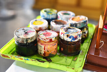 Many dirty painted jars of paint for art close up
