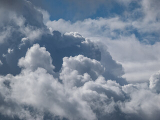 View of sky with fluffy white clouds in a sunny day. Background of dark sky sunlit with beautiful white clouds