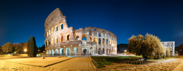 Rome, Italy. Colosseum Also Known As Flavian Amphitheatre In Evening Or Night Time. Panoramic View