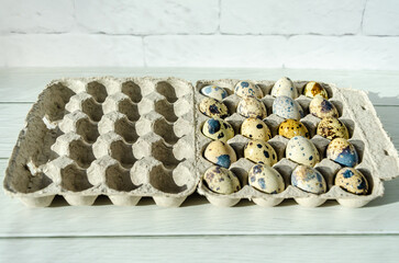 Quail eggs in eco-friendly packaging made from recycled paper, on white wooden table background