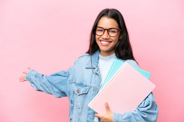Young student Colombian woman isolated on pink background extending hands to the side for inviting...