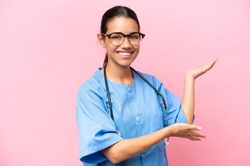 Young nurse Colombian woman isolated on pink background extending hands to the side for inviting to...