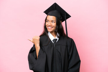 Young university Colombian woman graduate isolated on pink background pointing to the side to present a product