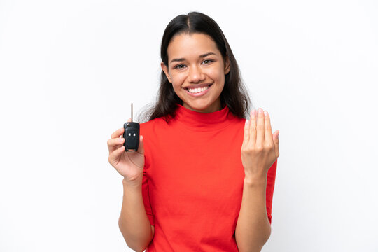 Young Colombian woman holding car keys isolated on white background inviting to come with hand. Happy that you came