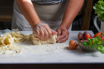 Woman in apron kneading fresh dough preparing hammed food on kitchen table, Food background, copy space.
