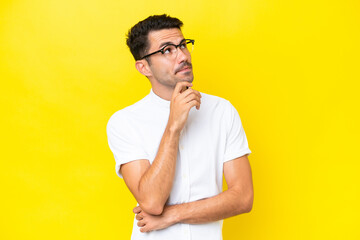 Young handsome man over isolated yellow background and looking up