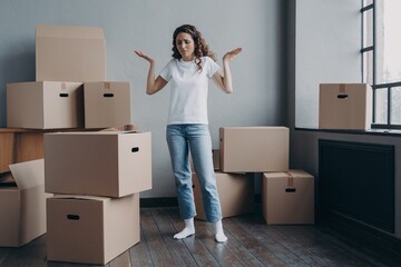 Puzzled tired woman with cardboard boxes feels exhausted of moving to new home. Hard relocation day