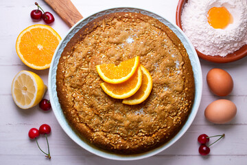 Orange sponge cake seen from above decorated with a few slices of fruit.