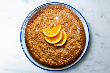 Orange sponge cake seen from above decorated with a few slices of fruit.