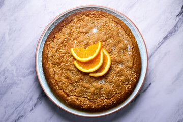 Orange sponge cake seen from above decorated with a few slices of fruit.