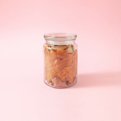 Minimal composition with glass jar full of dry leaves. Creative autumn food concept.