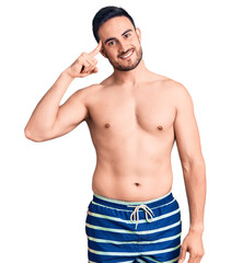 Fototapeta premium Young handsome man wearing swimwear smiling pointing to head with one finger, great idea or thought, good memory