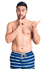 Fototapeta premium Young handsome man wearing swimwear asking to be quiet with finger on lips pointing with hand to the side. silence and secret concept.