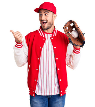 Young handsome man holding baseball gloves pointing thumb up to the side smiling happy with open mouth